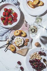 Baked Camembert or Brie with thyme and maple syrup. Flat lay of cheese, fruits, bread and nut to white wine.