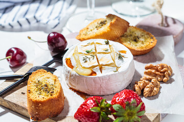 Baked Camembert or Brie with thyme and maple syrup. Cheese, fruits, bread and nut to white wine.