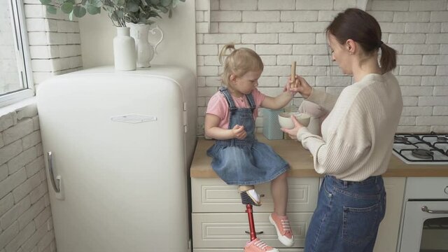 handicapped girl with mom preparing breakfast in kitchen