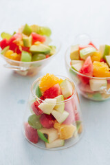 Pieces of tropical fruits in a glass. Sliced orange, apple, slices of watermelon in glass bowl. Citrus fruits