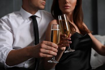 Beautiful couple with glasses of champagne indoors, closeup. Luxury lifestyle