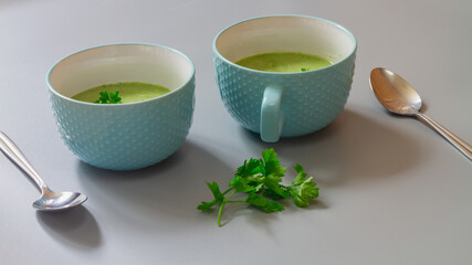 Green cabbage broccoli soup in plates decorated with parsley leaves