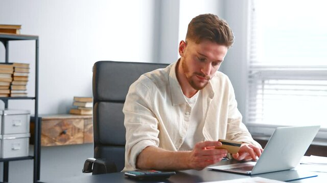 Bearded businessman in yellow shirt enters bank card info