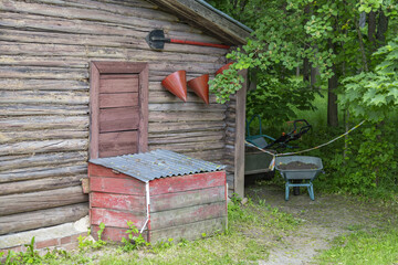 Wooden box with sand, old fire-fighting tools and garden equipment against the wall of a small country house