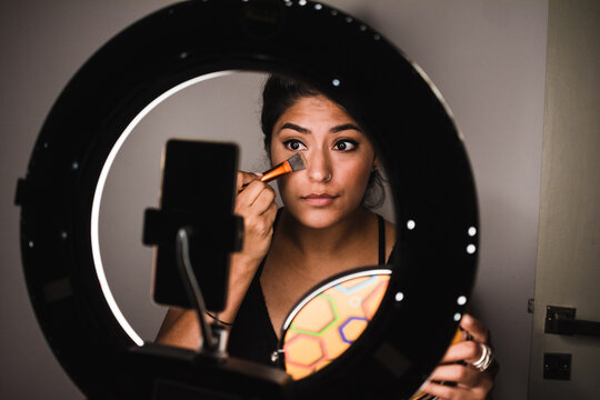 Woman applying foundation on online class