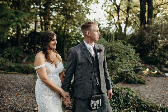 Smiling Bride and Groom Walking in Forest