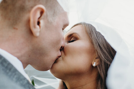 Romantic Wedding Couple Kissing under Veil