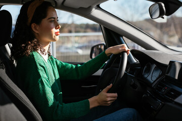 Young female driver steering car in outskirts
