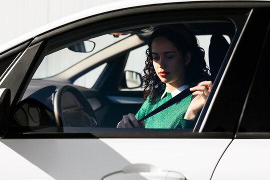 Female driver fastening safety belt in car