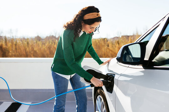 Young woman on electric car charge station