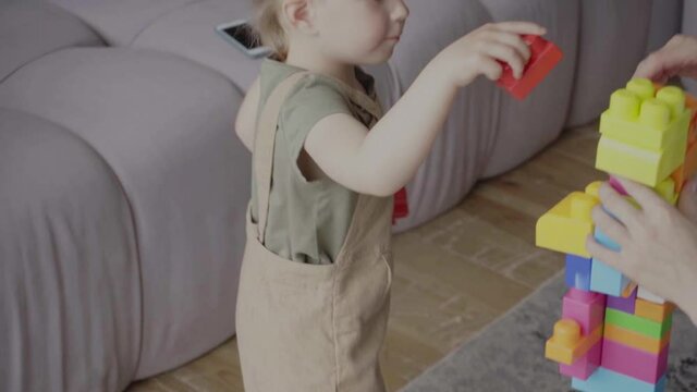 Amputee Child Making Tower From Building Blocks With Mother