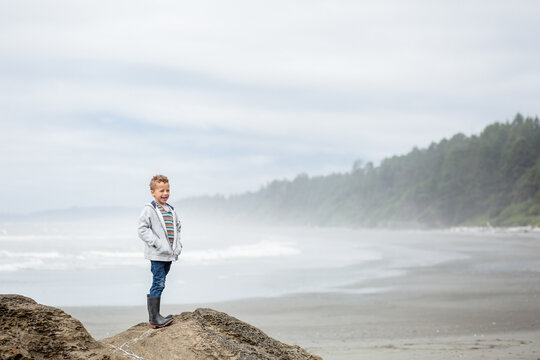 Boy stands proudly on rocky overlooking coast