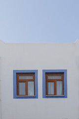 A white building with blue window frames against a blue sky in the Greek style. Travel and architecture concept. High quality photo
