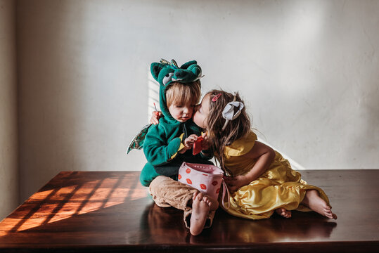 Sister in costume kisses toddler brother
