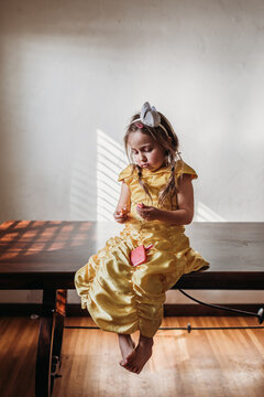 4 year old girl in yellow dress playing with makeup at home. 
