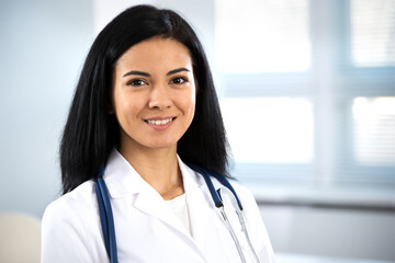 Сlose-up portrait of smiling hispanic female doctor.