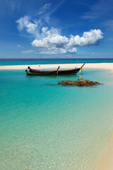 long tail boat, in white sand beach in the andaman sea