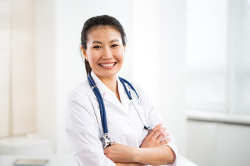 Portrait of smiling asian female doctor in a gray background for your text.