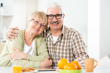Happy elderly couple hugging at home and smiling