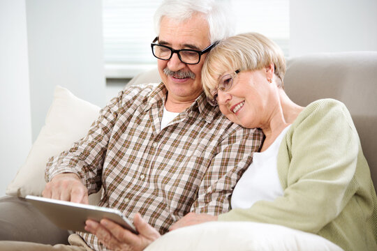 Elderly couple talking using tablet computer together at home