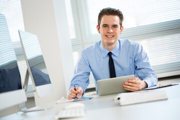 Portrait of young businessman working with laptop at office