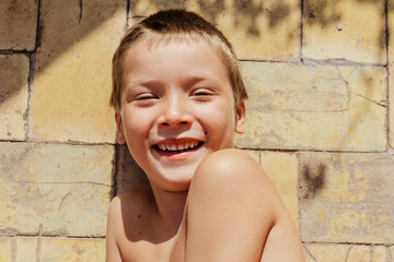 smiling boy looking at camera on wall outdoors