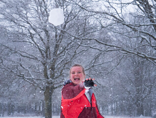 Smiling girl is throwing a snowball 