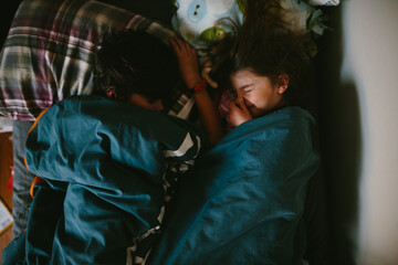 overhead view of children sleeping and sister plugging her nose