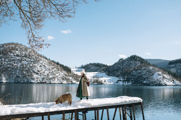 Young woman and her dog standing on  the dock