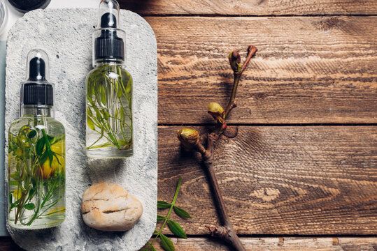 Aromatic oils with herbs in transparent bottles on wooden background