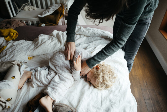 Father tickle his son on the bed