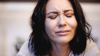 portrait of crying brunette woman with closed eyes on beige background