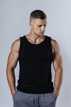 Muscular man wearing blank black tank top against gray background