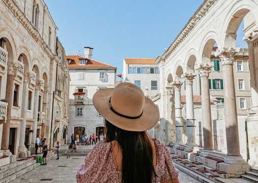 Rear view of young female tourist admiring the Peristyle in Diocletian's palace in Split, Croatia.
