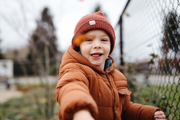 Toddler boy throwing leaves at the camera