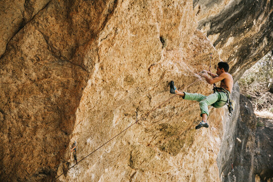 Adventurer man wearing safety harness climbing mountain