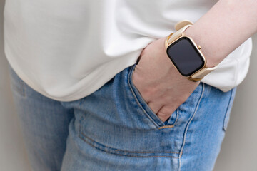 Young woman wear blue jeans and white shirt show hand with golden smart watch.
