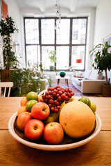 A bowl of fruit sits on a table in an apartment.