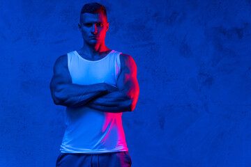 Handsome and confident bodybuilder posing in colorful light - Powered by Adobe