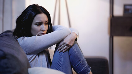 Obraz premium depressed woman sitting on sofa in self hug pose at home