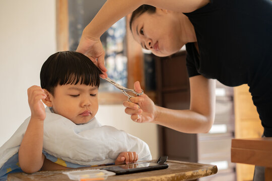 Asian mother cutting hair to her son