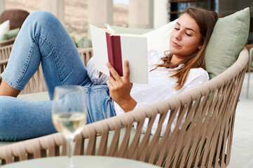 Woman reading a book with a glass of wine