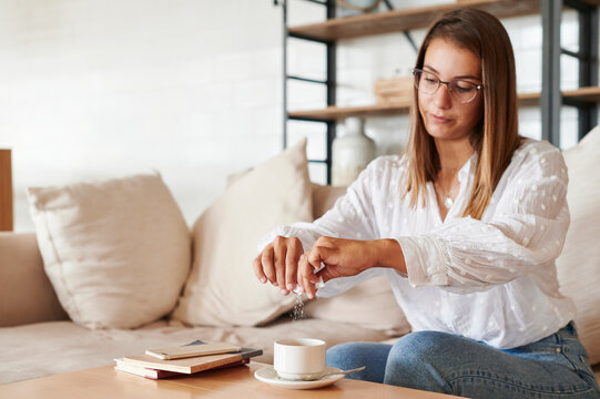 Woman putting sugar in her tea at home