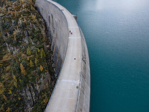 people walking on the edge of water dam,  aerial view, renewable energy