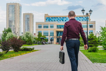A man with a briefcase going to work in an office building. Back view of office worker walking with briefcase to work