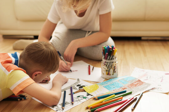 Happy mother and son are drawing together at home