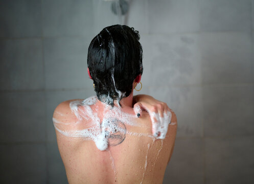 Anonymous woman washing skin in shower
