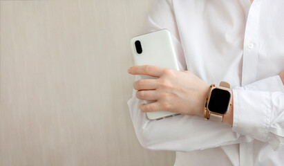 Office clerk wear white classic shirt  and smartwatch holding modern white smartphone in hand.
