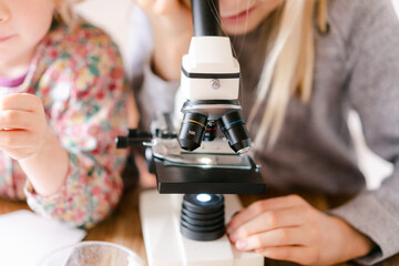 young girl and little sister looking through microscope 