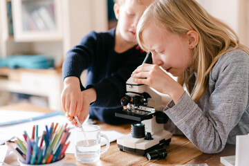 young girl and little brother looking through microscope